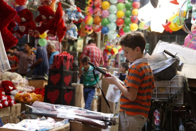 A child inspects a toy gun in Al-Asrouniyeh souk ahead of Eid al-Fitr celebrations in Damascus July 27, 2014.  REUTERS/Omar Sanadiki (SYRIA - Tags: RELIGION SOCIETY)