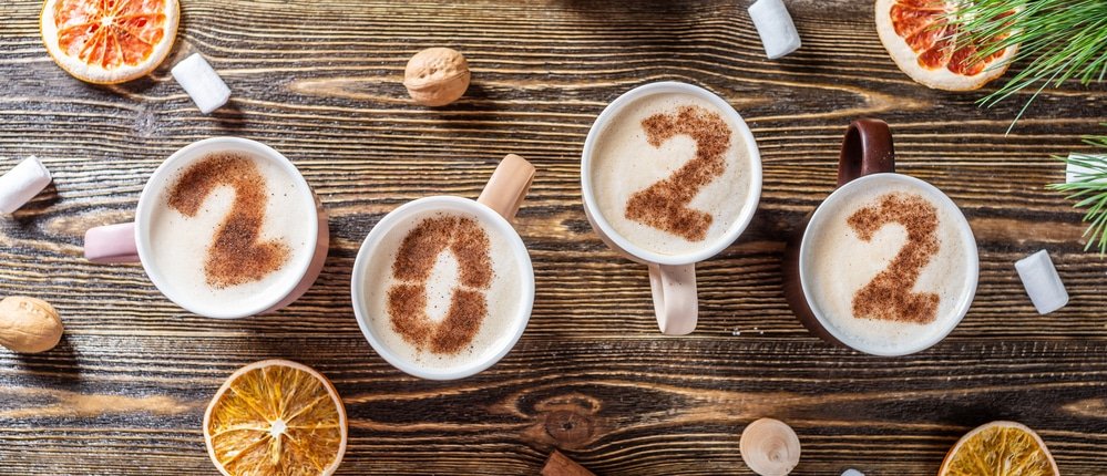 Card with numbers 2022 for New year and Christmas. Cup of coffee with figures on wooden background. Top view. Flat lay